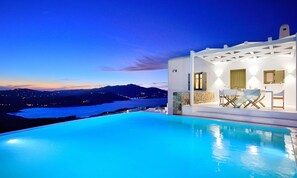 A poolside area with a view of the sea and mountains at dusk. - Mykonos Ark Villas (Mykonos)