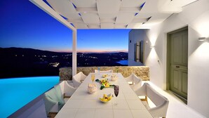 A dining area with a table set for two, overlooking a cityscape at dusk.