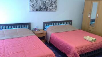 Een hotelkamer met twee bedden, een nachtkastje, een garderobe en een stadsgezichtschilderij aan de muur.