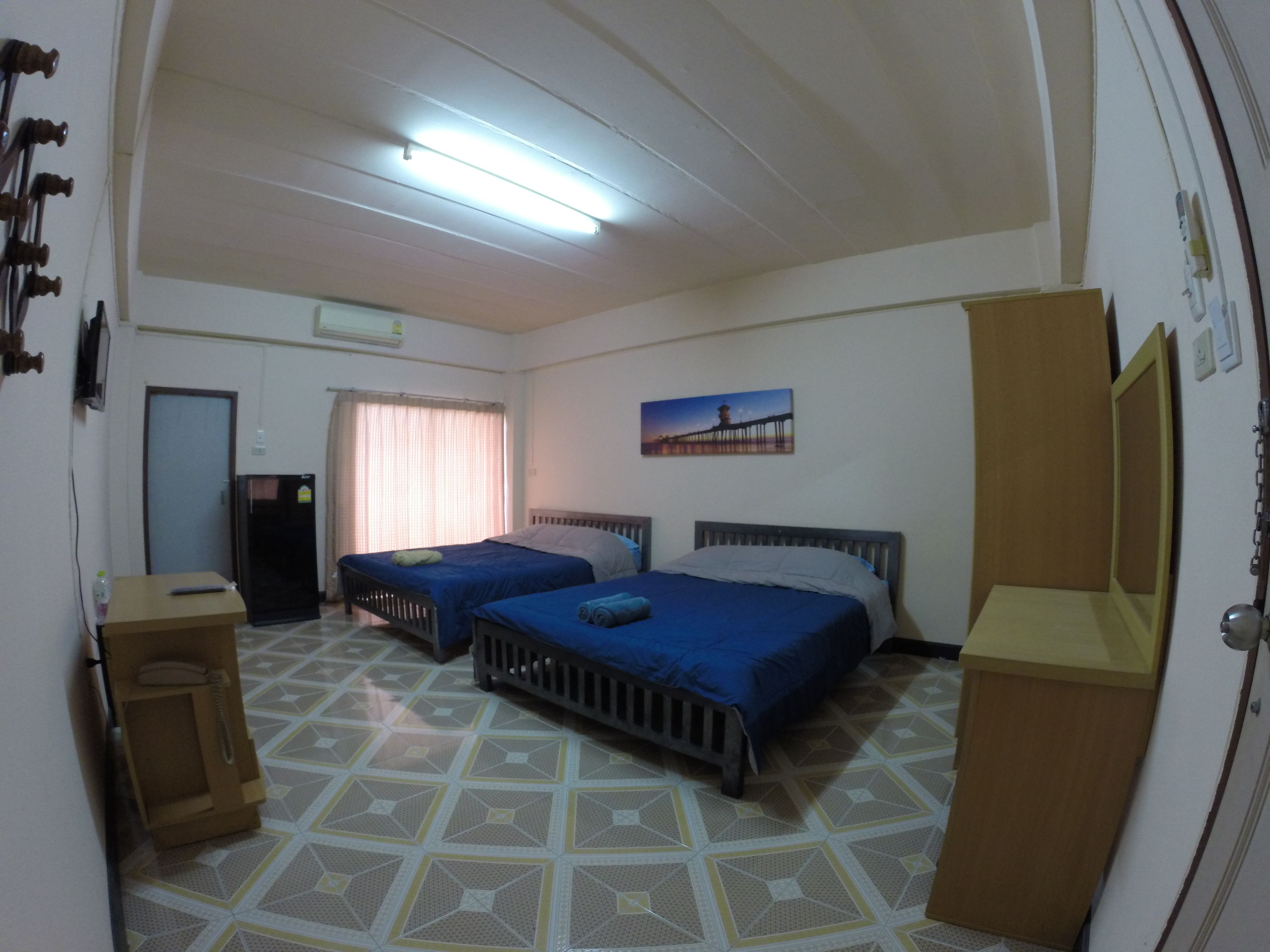 A room with two beds, a desk, a mirror, and a door.