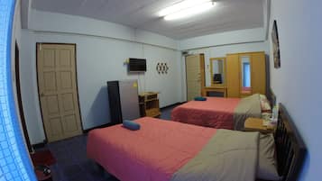 A hotel room with two beds, a television, a refrigerator, a mirror, and a door.