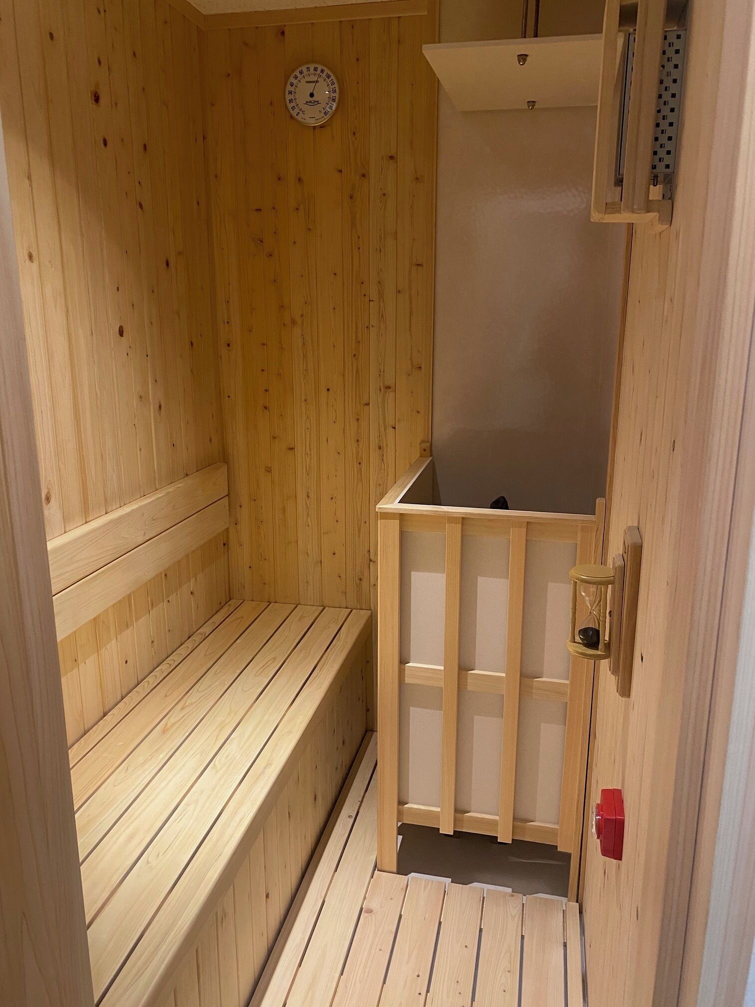 A wooden sauna with a bench, a small shelf, and a wall-mounted clock.