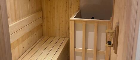 Uma sauna de madeira com um banco, uma prateleira pequena e um relógio fixado na parede.