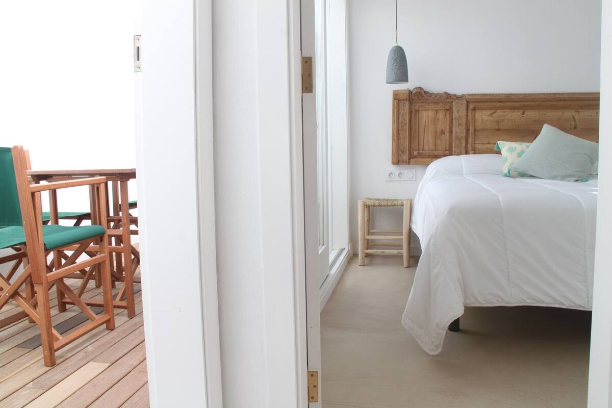 A bedroom with a wooden headboard, a bed with white bedding, and a small wooden nightstand.