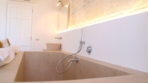 Un baño moderno con una bañera independiente, un cabezal de ducha y un espejo grande sobre el lavamanos.