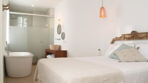 Un dormitorio con una cama, cabecera de madera, mesita de noche y un espejo montado en la pared.
