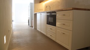 Una cocina con armarios blancos, horno empotrado y campana extractora de acero inoxidable.