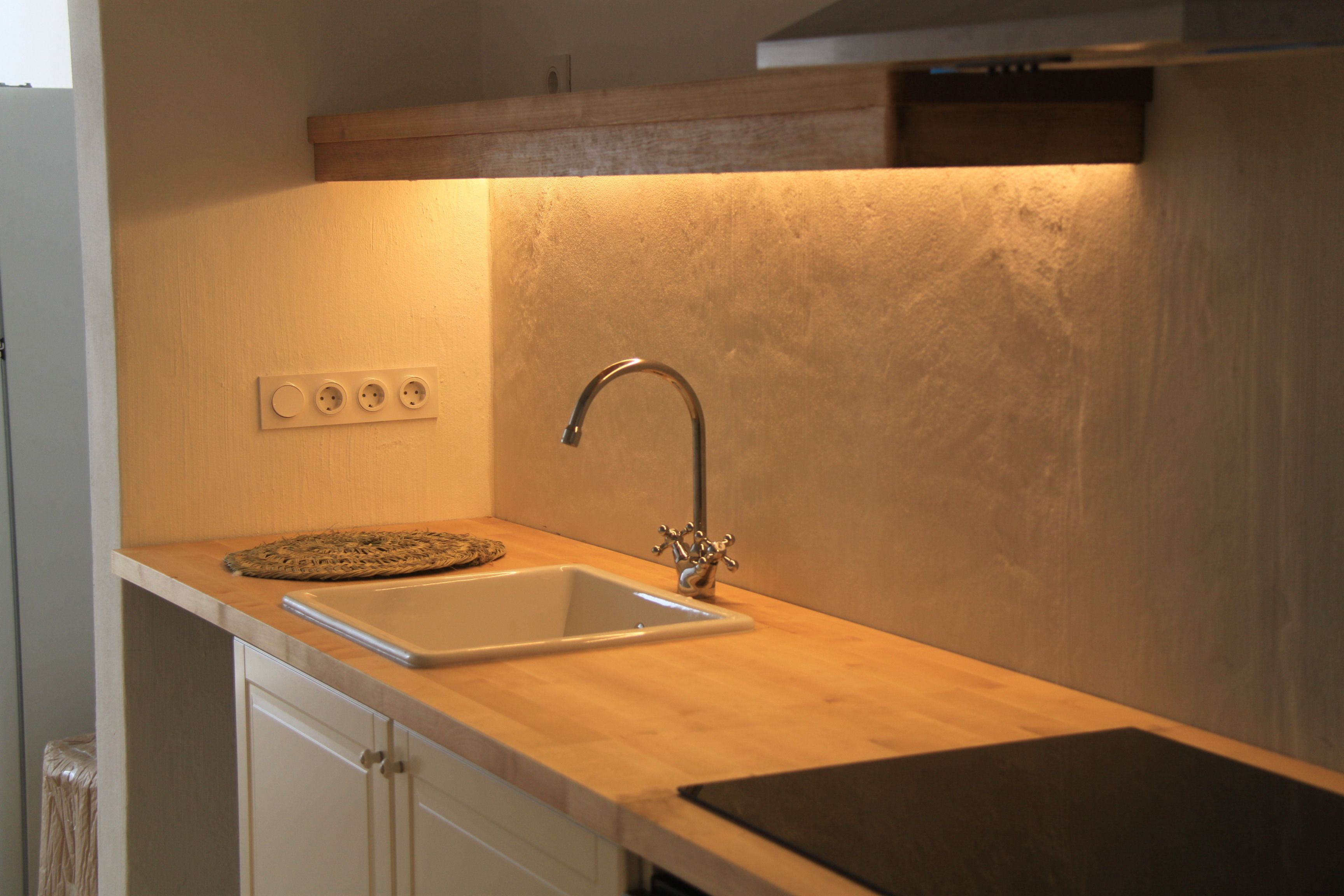 Una cocina con lavamanos, encimera y salpicadero de madera.