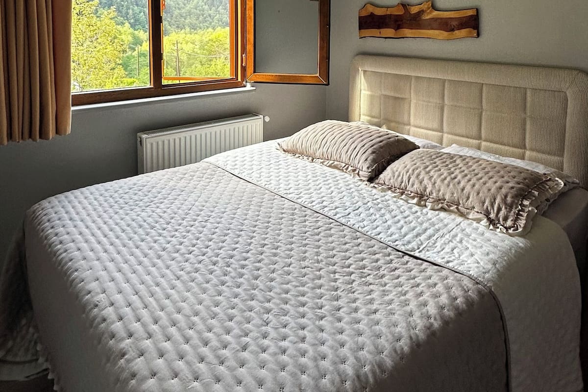 Un dormitorio con una cama grande, una ventana con cortinas, un radiador y una decoración mural de madera.