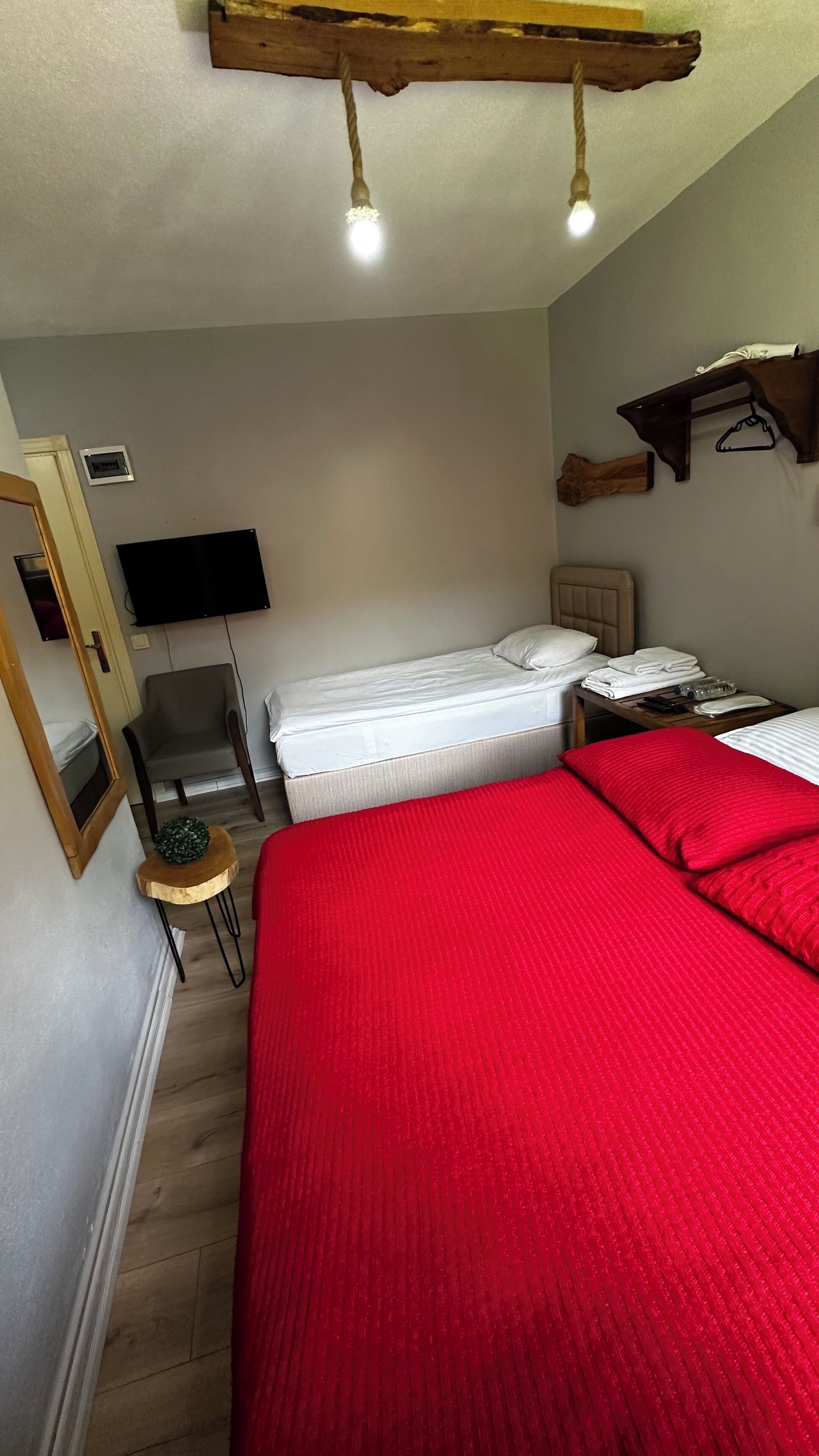 Une chambre à coucher comprenant un lit, une chaise, une petite table, un téléviseur et une poutre en bois au plafond.