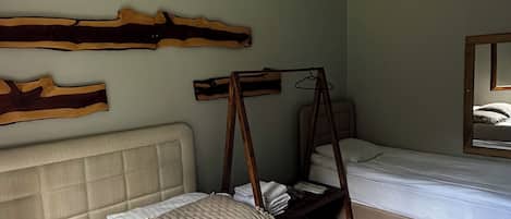 Una habitación con dos camas, una lámpara de techo de madera y un espejo en la pared.