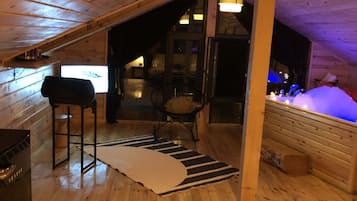 A cozy wooden cabin with a loft bedroom, a dining area, and a bathroom with a bathtub.