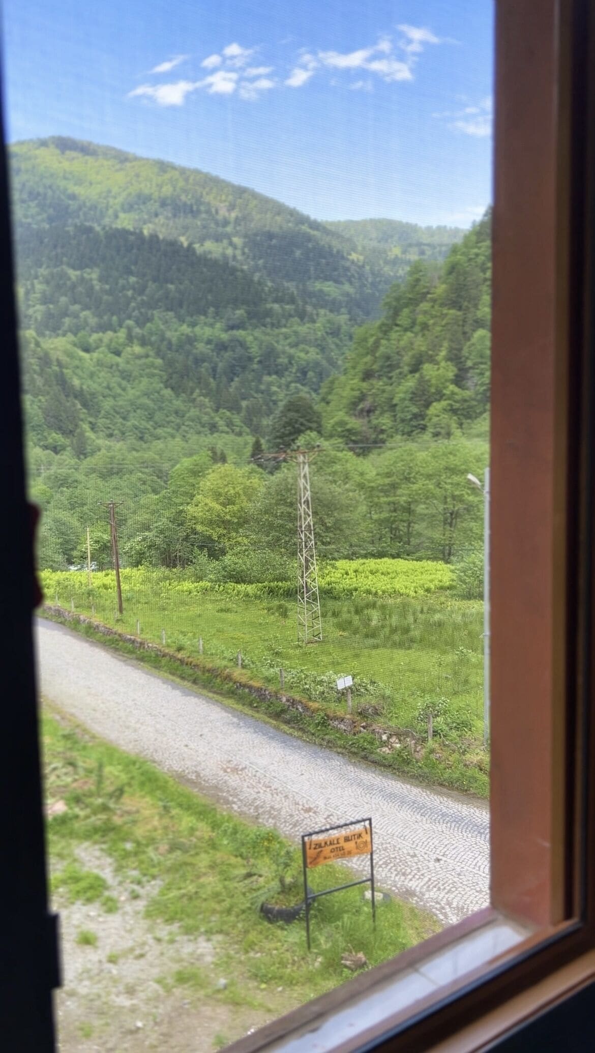 Paisaje rural con camino, señal y línea eléctrica.