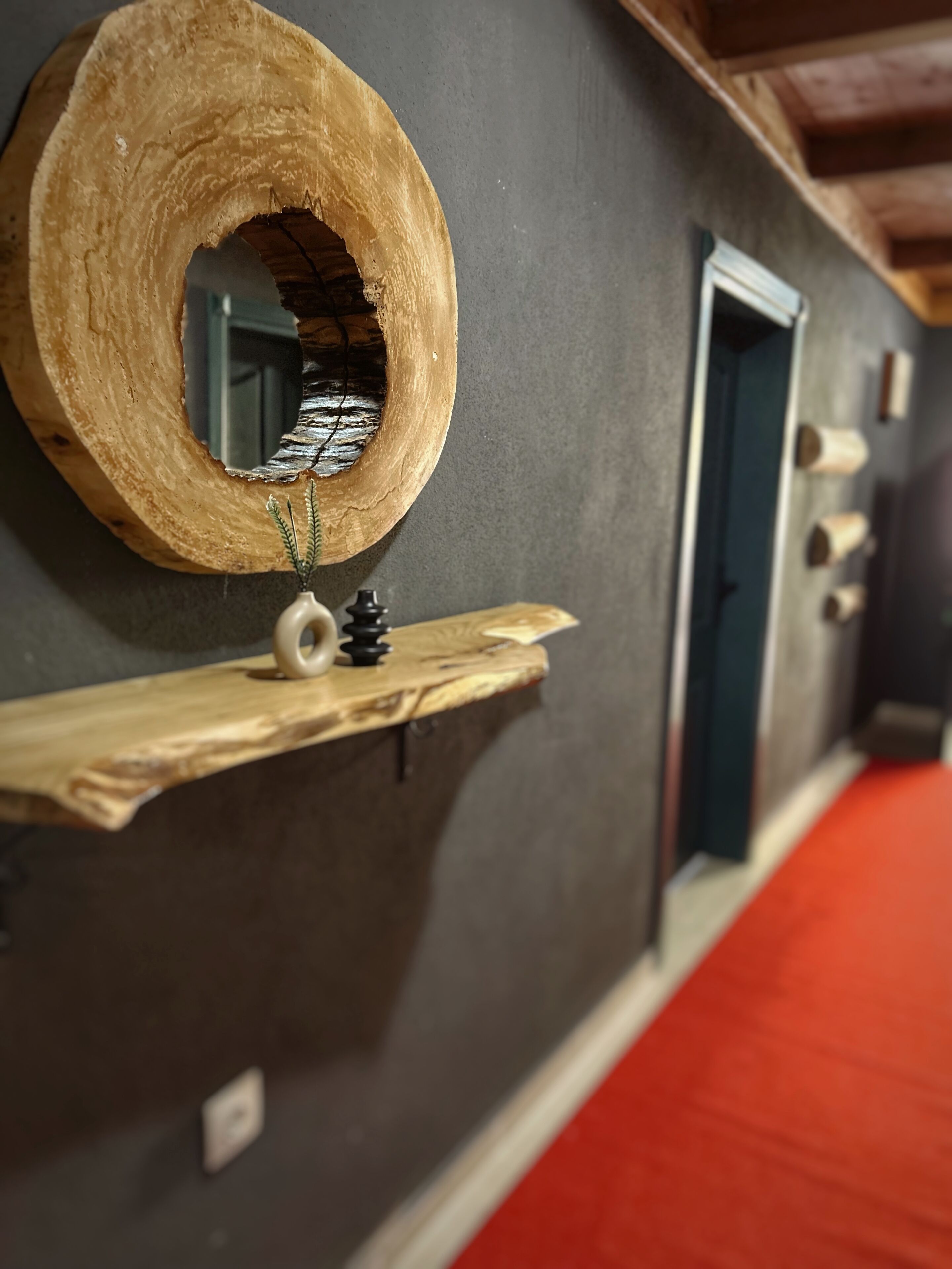 Un pasillo con decoración de madera en la pared, un espejo y una puerta.