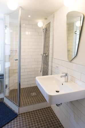 A modern bathroom with a glass shower enclosure, a white sink, and a large mirror. - KONCEPT Hotel Zum Kostbaren Blut (Cologne)