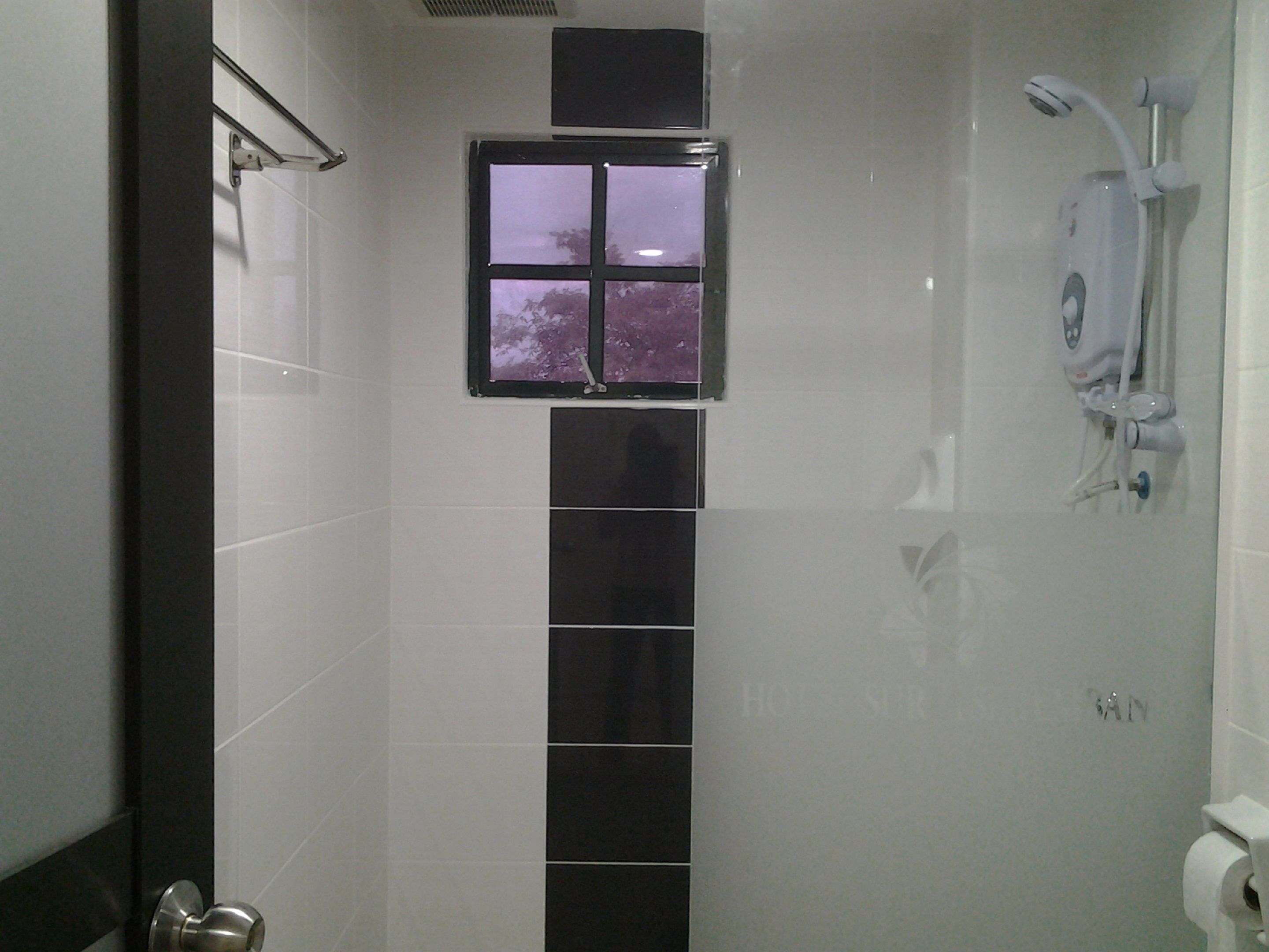 A bathroom with a shower, a window, and a toilet.