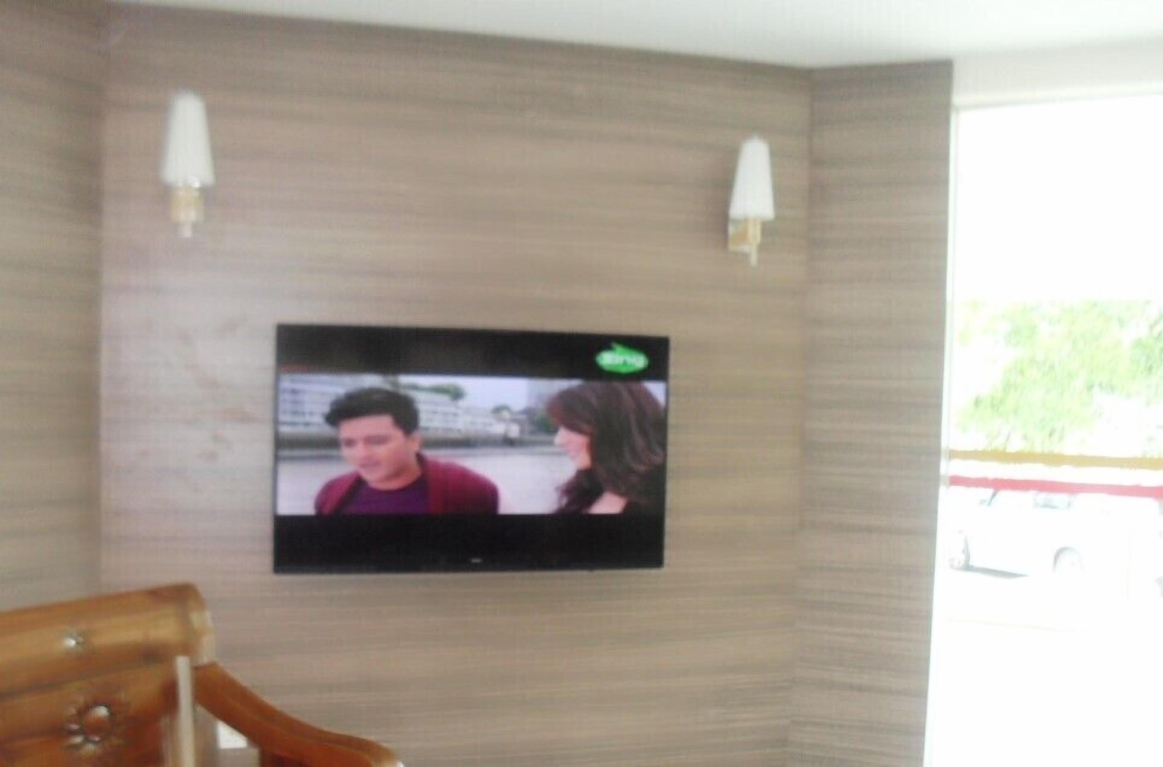 A television mounted on a wall with two wall sconces.