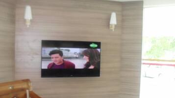 A television mounted on a wall with two wall sconces.