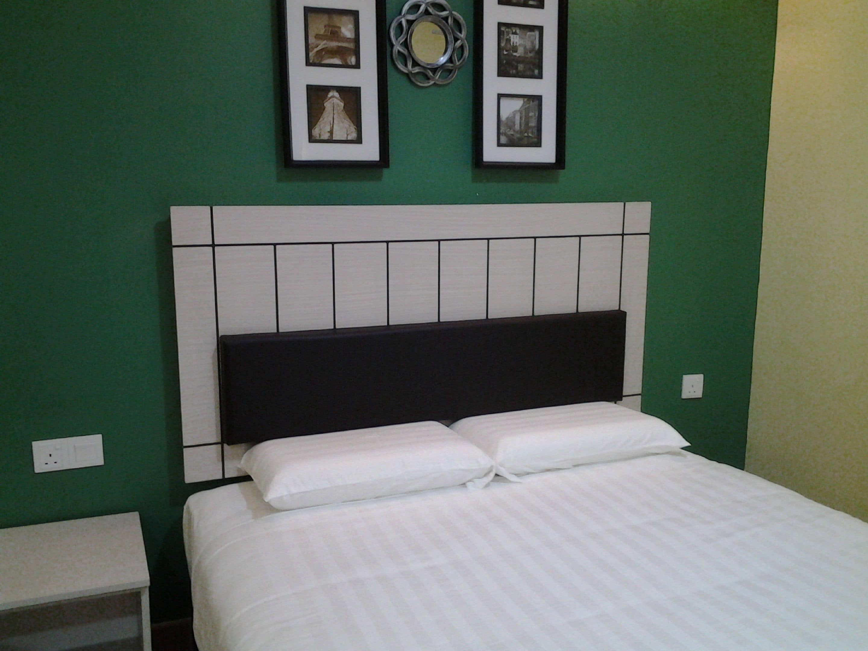 Ein Schlafzimmer mit einem Bett, einem Nachttisch und einer Wand mit gerahmten Bildern.