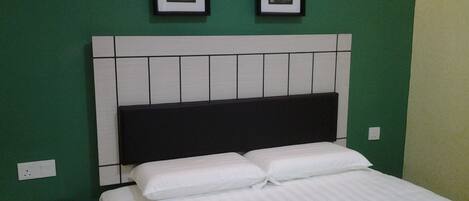 A bedroom with a bed, a nightstand, and a wall with framed pictures.