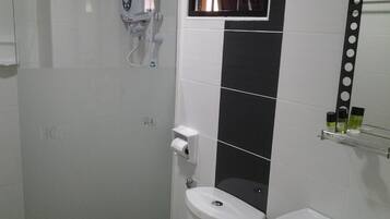 A bathroom with a toilet, sink, and a mirror with a black tile backsplash.