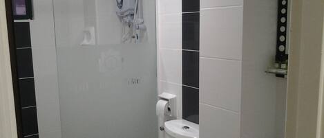 A bathroom with a shower, toilet, and a sink.