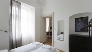 A hotel room with a bed, a dresser, a mirror, and a painting on the wall. - Heart of Vienna Apartments (Vienna)