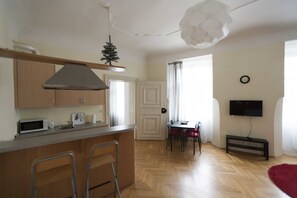 A compact kitchen with a microwave, a small island with stools, a ceiling fan, and a dining area with a table and chairs.