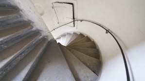 A spiral staircase with a handrail and a wall-mounted electrical outlet. - Heart of Vienna Apartments (Vienna)