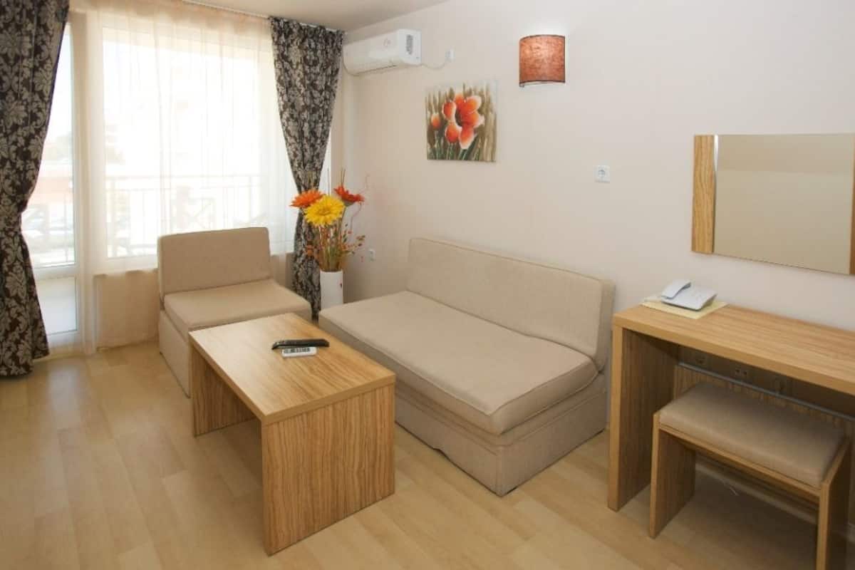 Una habitación moderna con un sofá, una mesa de madera, un pequeño banco y un escritorio con una lámpara.
