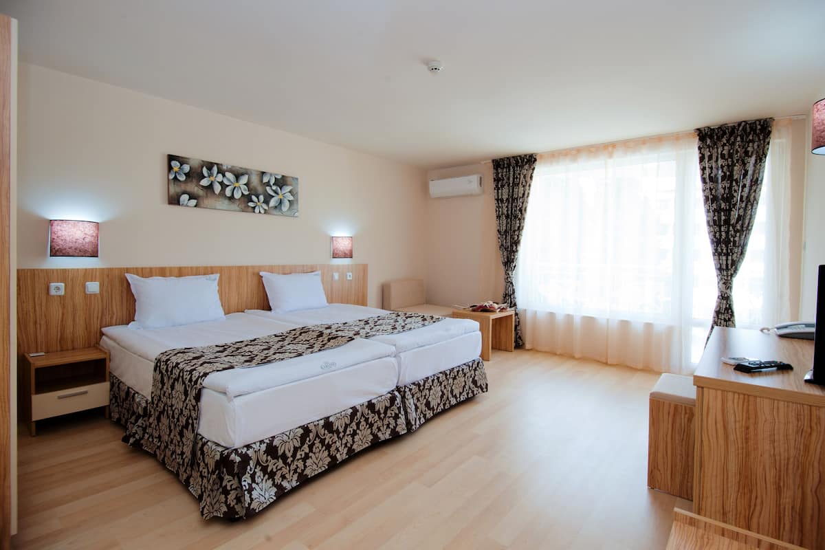 Habitación de hotel con una cama grande, mesitas de noche, un escritorio y un televisor.