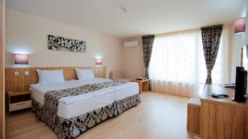 A hotel room with a large bed, bedside tables, a desk, and a TV.