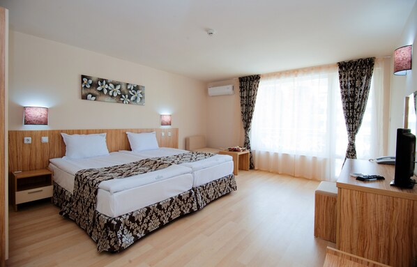 A hotel room with a large bed, bedside tables, a desk, and a TV.