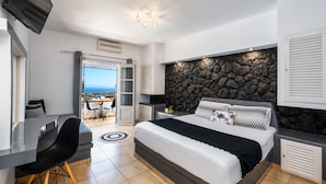 A modern bedroom with a bed, a desk, and a view of the outdoors. - Plastiras Rooms (Santorini)