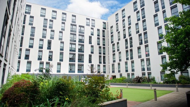 A modern multi-story building with a courtyard featuring green grass and plants. - CityLiveIn London Wembley (Wembley)