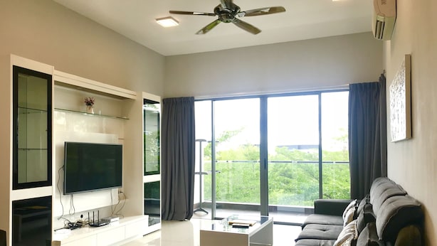 Un salon moderne doté d’un téléviseur à écran plat, d’une grande fenêtre avec des rideaux, d’un ventilateur de plafond et d’un canapé d’angle.