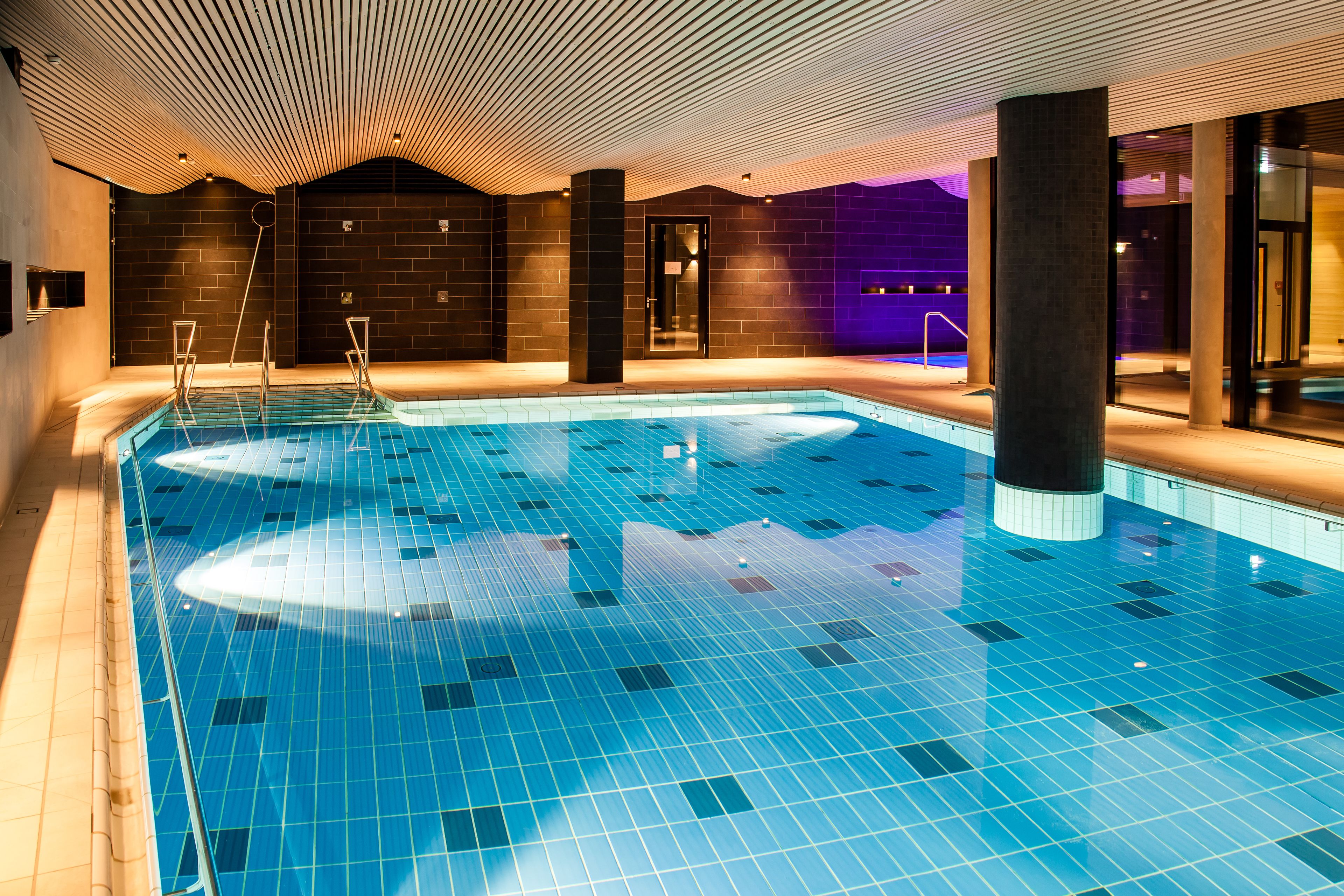 Ein Hallenbad mit Fliesenboden und Holzbalkendecke.