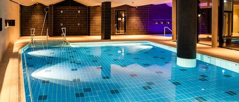 An indoor swimming pool with a tiled floor and a wooden ceiling.