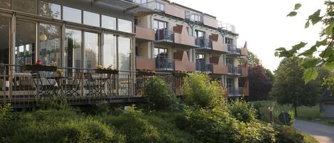 Un edificio residencial de varios pisos, con balcones, ventanas amplias y un jardín.