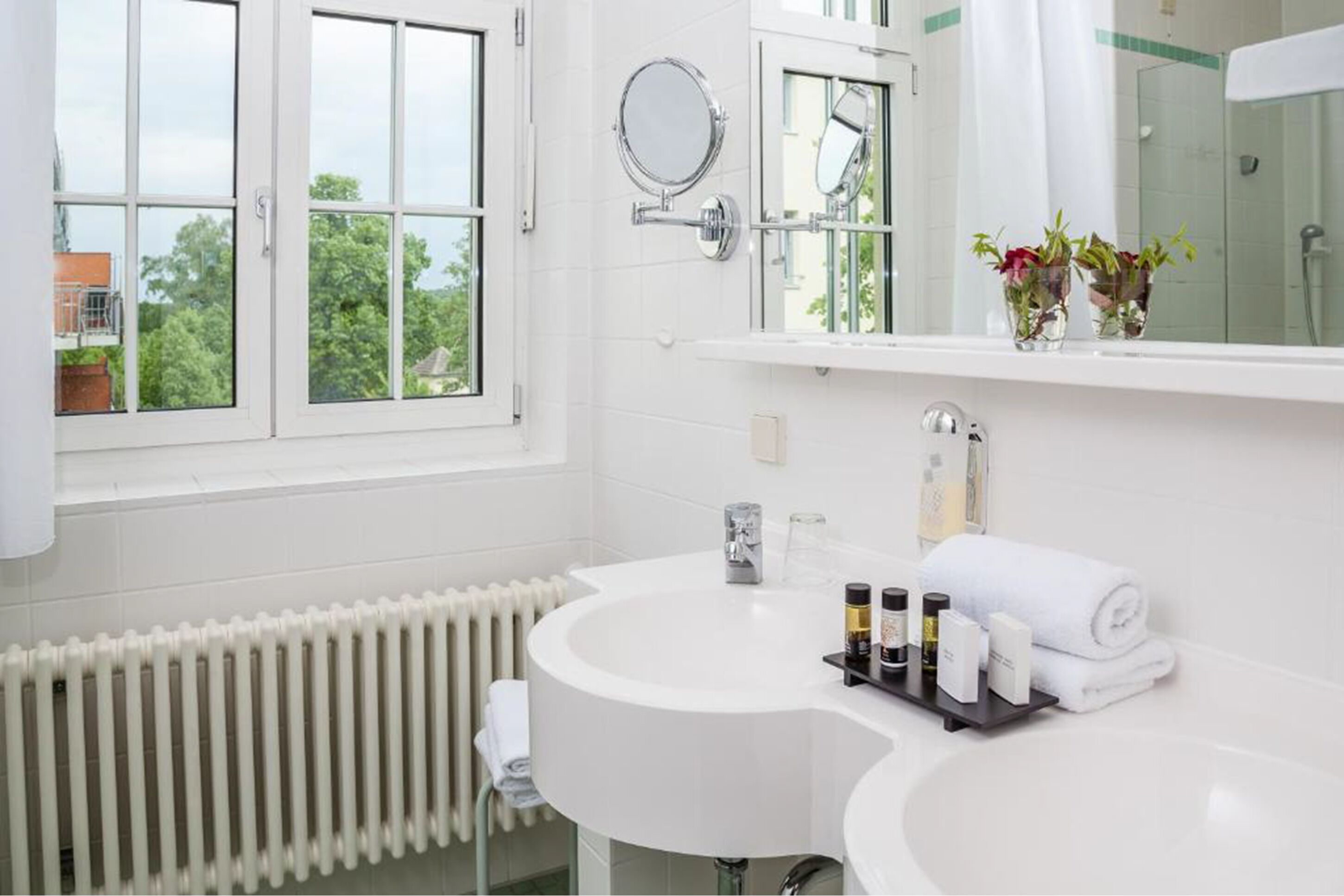 Un baño moderno con un lavamanos blanco, un espejo y una ventana.