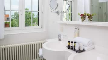Un baño moderno con un lavamanos blanco, un espejo y una ventana.