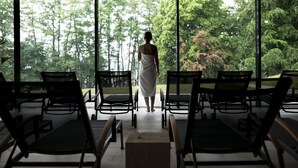 A person in a white towel walking towards a window overlooking a garden. - Spa Hotel Amsee (Waren (Müritz))