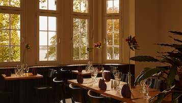 A dining area with tables set for four, large windows, and chairs.