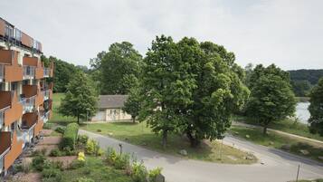 Ein mehrstöckiges Gebäude mit Balkonen, ein kleiner Garten mit einem Pfad und Blick auf einen See.