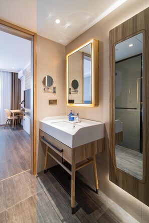 Une salle de bain moderne avec un grand miroir, un lavabo et un espace douche.