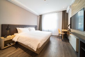 A hotel room with a large bed, bedside table with a phone, a desk with a chair, and a TV. - Hanting Hotel (Beijing)