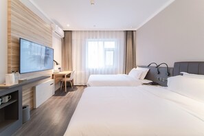 Une chambre d’hôtel comprenant un lit, une table de chevet, une télévision et un bureau avec une chaise.