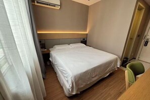 Ein Hotelzimmer mit Bett, Nachttisch, Stuhl und Tür.