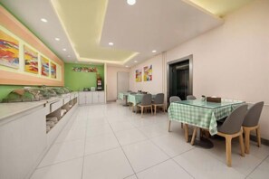 A dining area with a glass table, chairs, and a counter with food items.