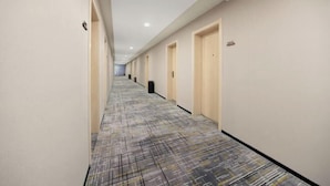 A hotel corridor with doors on both sides, carpeted floor, and a ceiling with recessed lighting. - Ginza Jiayi Hotel (Yantai Suocheng Wanda Plaza Branch) (Yantai)